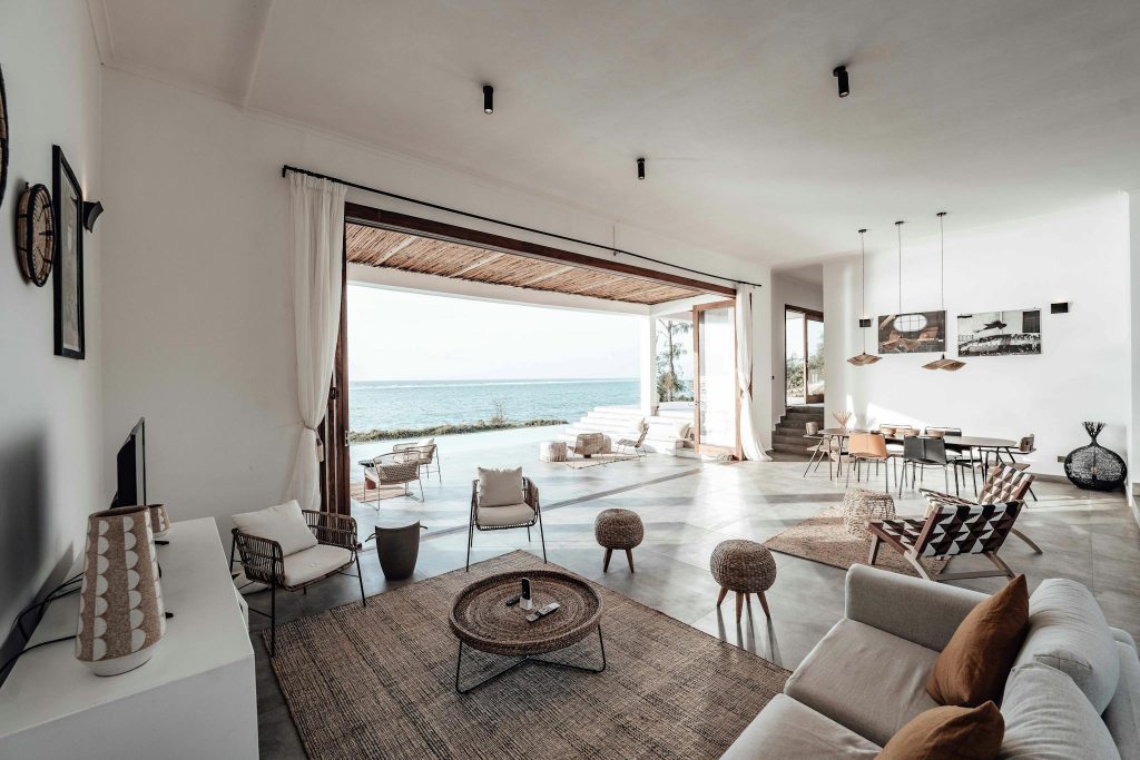 A spacious, minimalistic living room with a stunning ocean view, showcasing modern interior design.