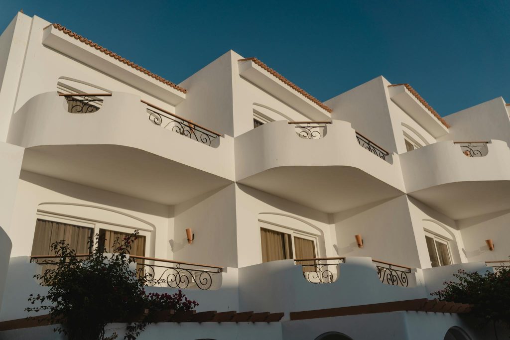 Elegant white Mediterranean building with ornate balconies under a clear blue sky.